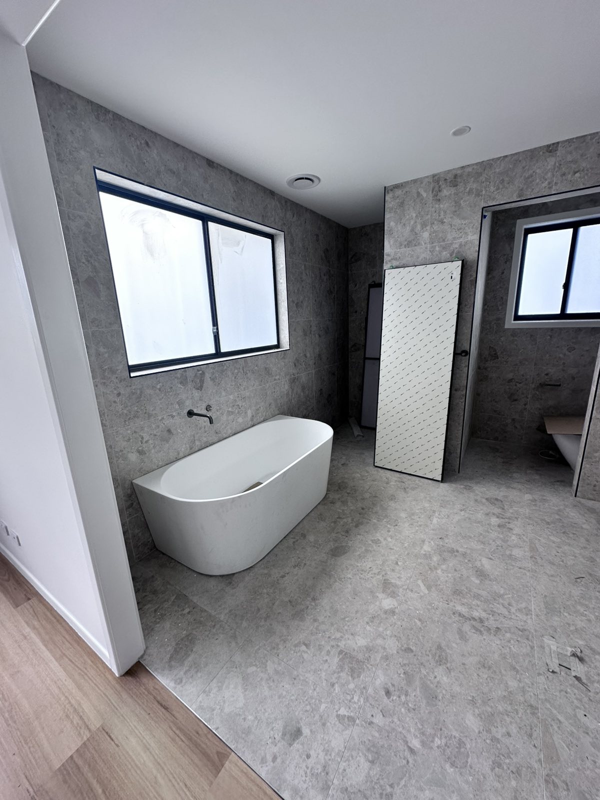Ensuite bathroom with freestanding bath and grey stone tiling