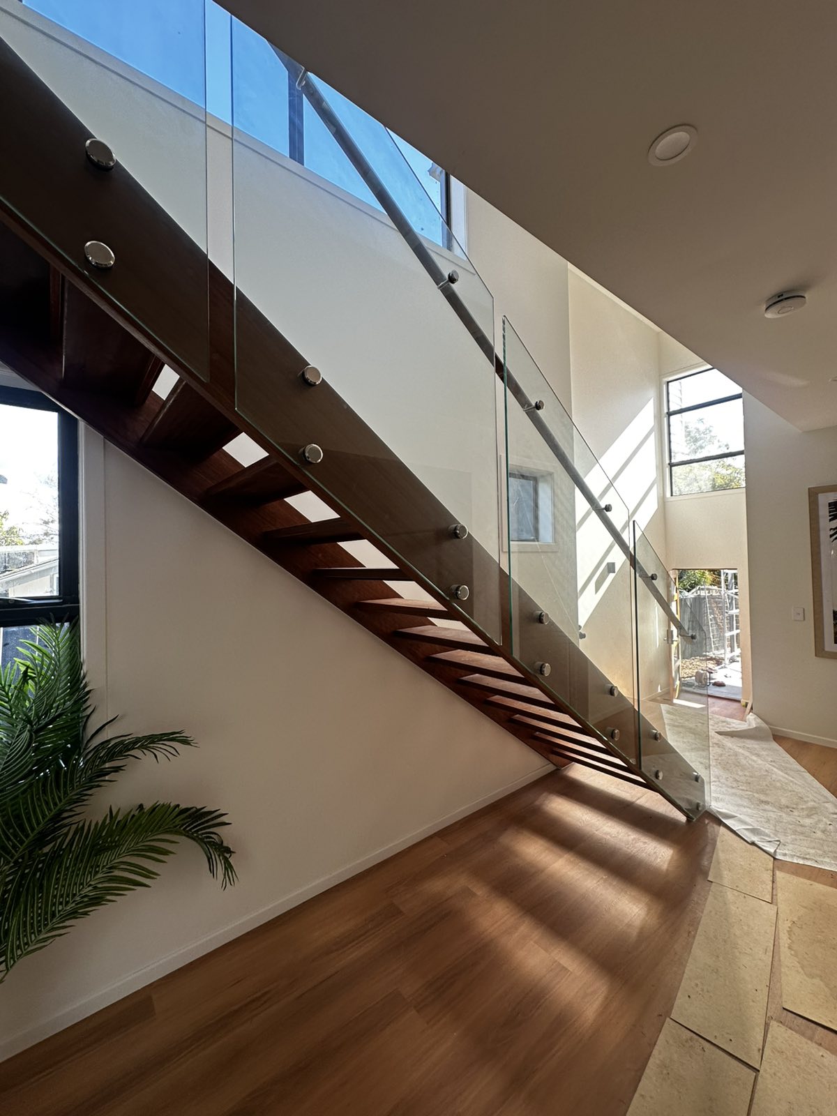 Timber staircase with glass balustrade beneath a skylight